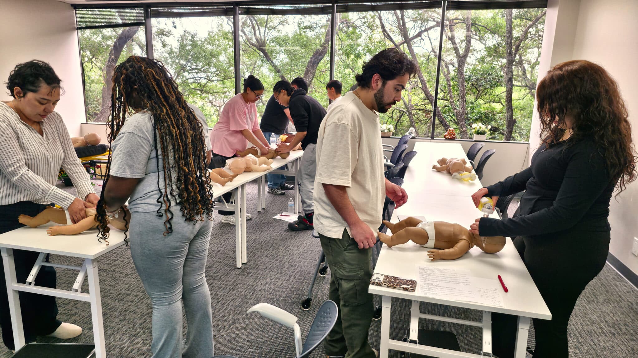 Students practicing two-person rescue CPR on infant manikins during Cardiox Care BLS training